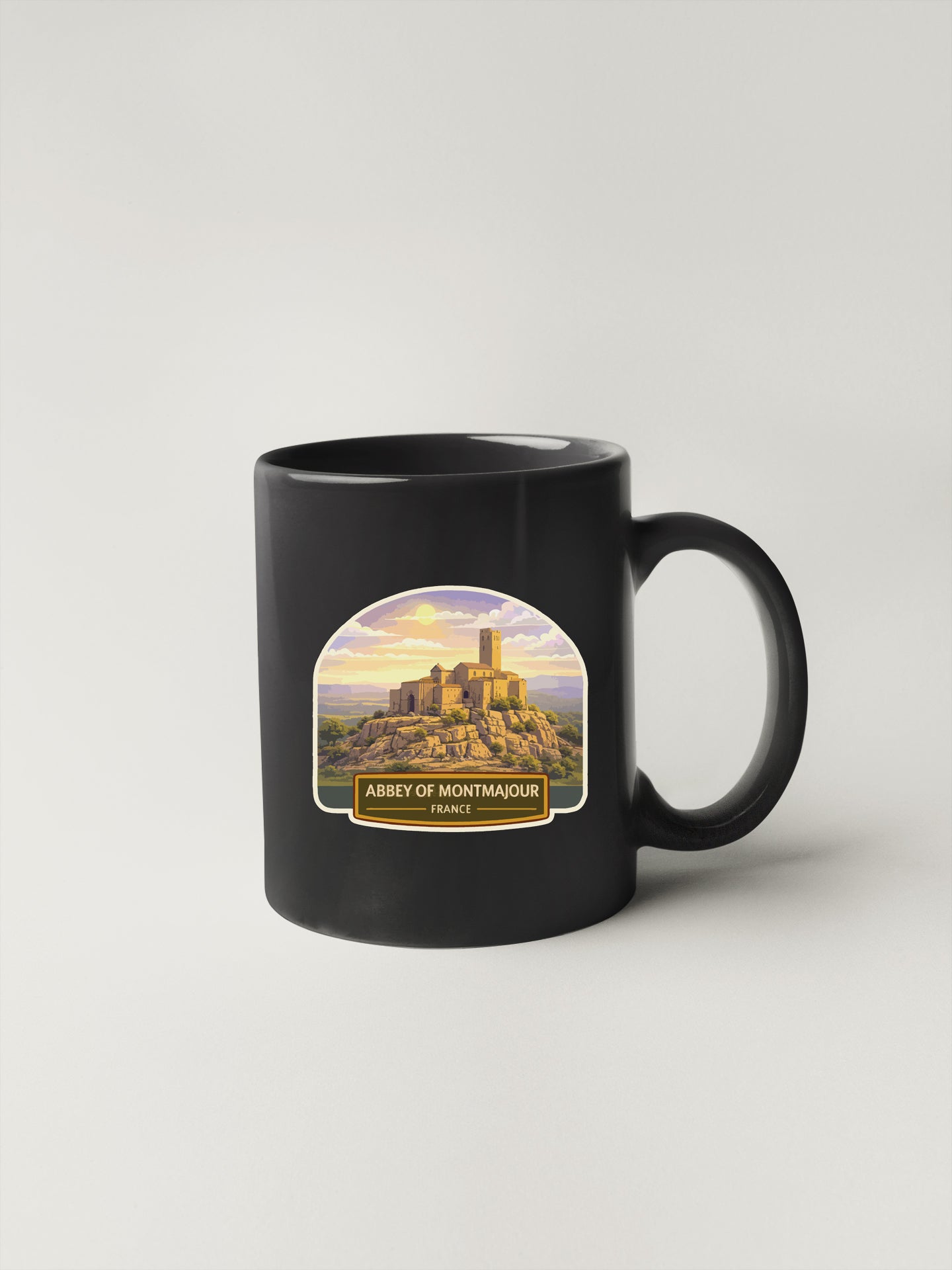 A black coffee mug with a graphic of the Abbey of Montmaour in France.