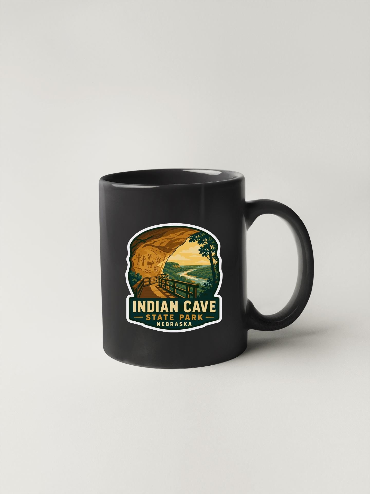 A black coffee mug with a graphic design depicting the Indian Cave State Park in Nebraska.