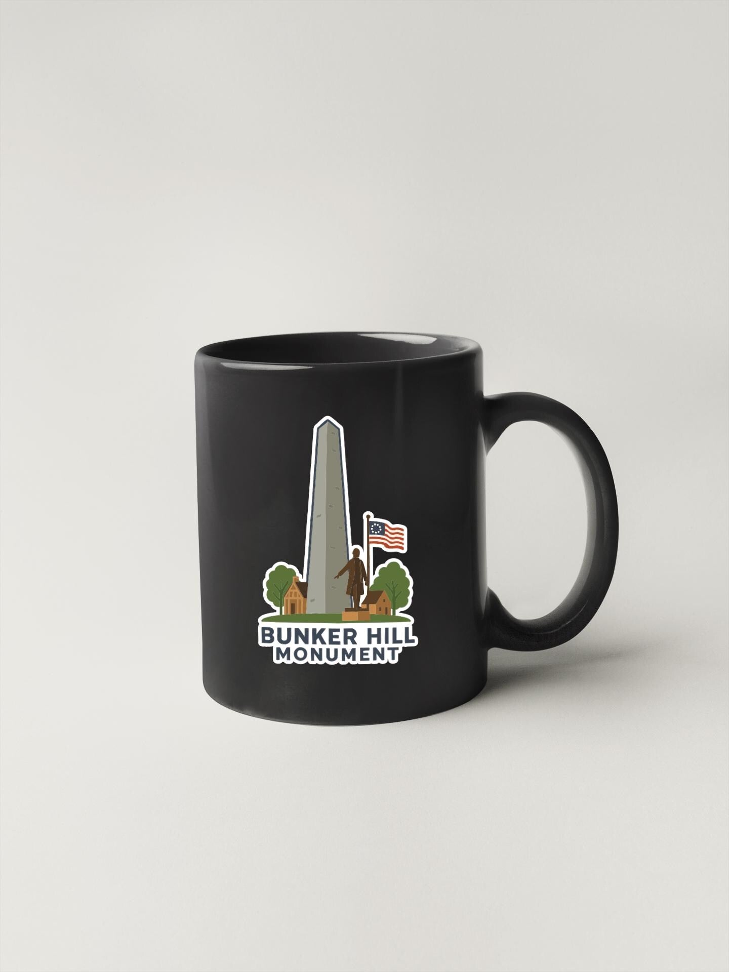 A black coffee mug with a graphic design depicting the Bunker Hill Monument, an American military base located in Philadelphia, Pennsylvania.