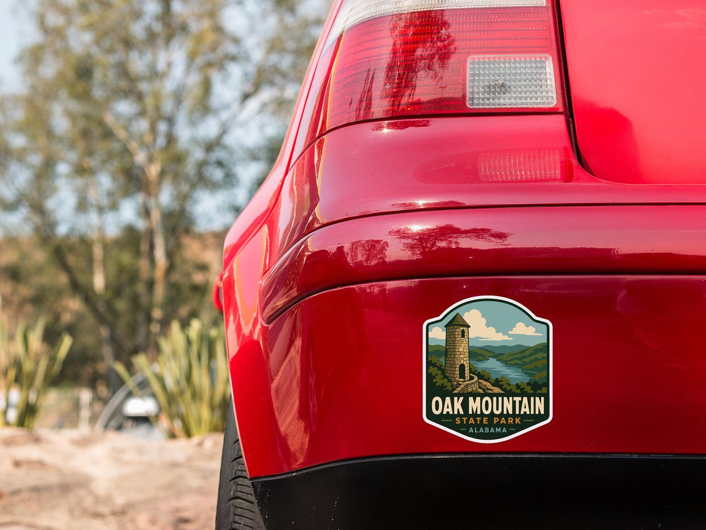 the rear end of a red car with a sticker on the trunk that says "OAK MOUNTAIN STATE PARK ALASKA".