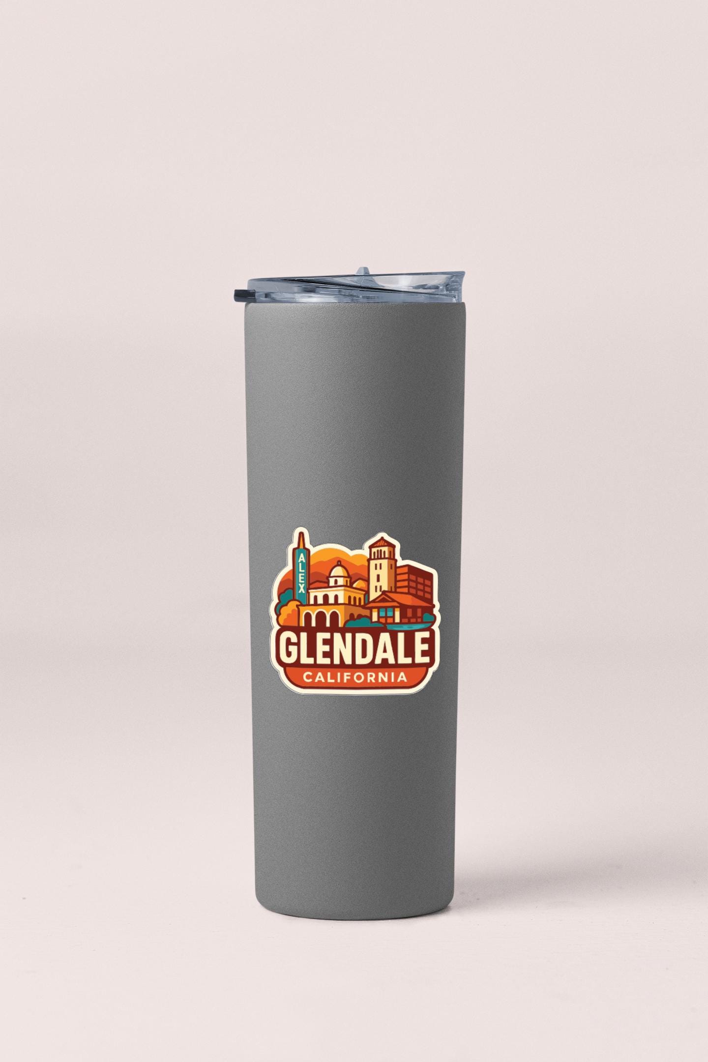 A gray insulated tumbler with a lid and a sticker featuring the Glendale, California skyline.