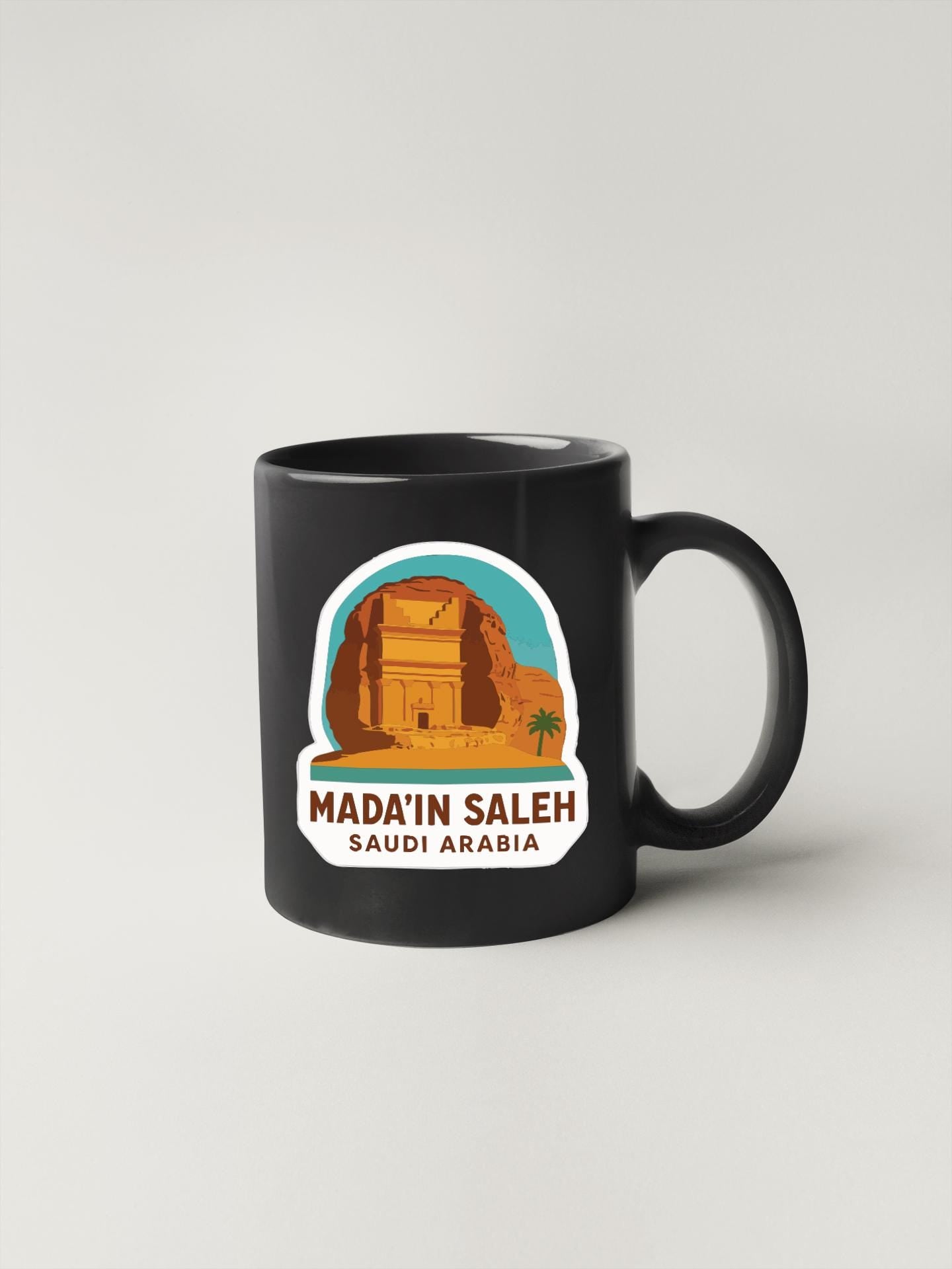 A black coffee mug with a graphic design depicting the ancient city of Madinat SalEH in Saudi Arabia.