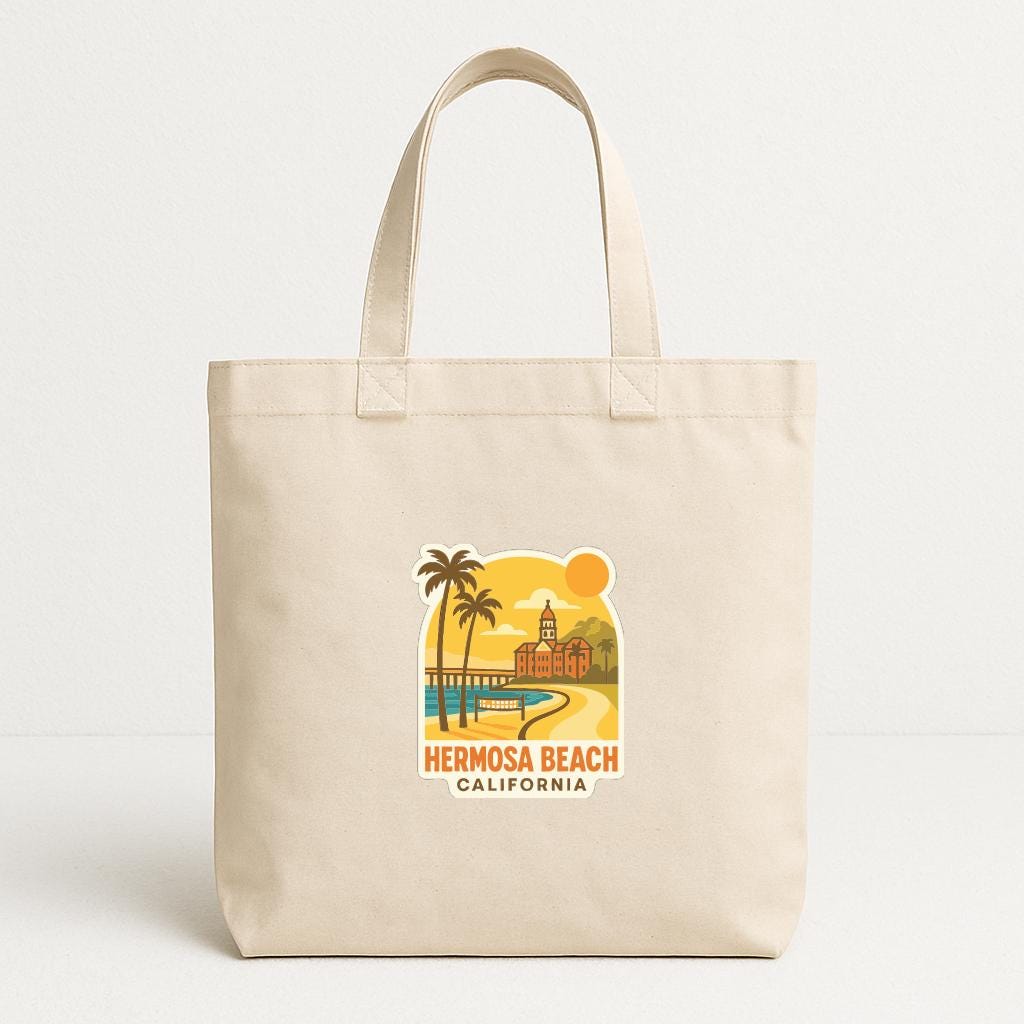 A beige tote bag with a printed design depicting a beach scene with palm trees, a building, and a sunset.