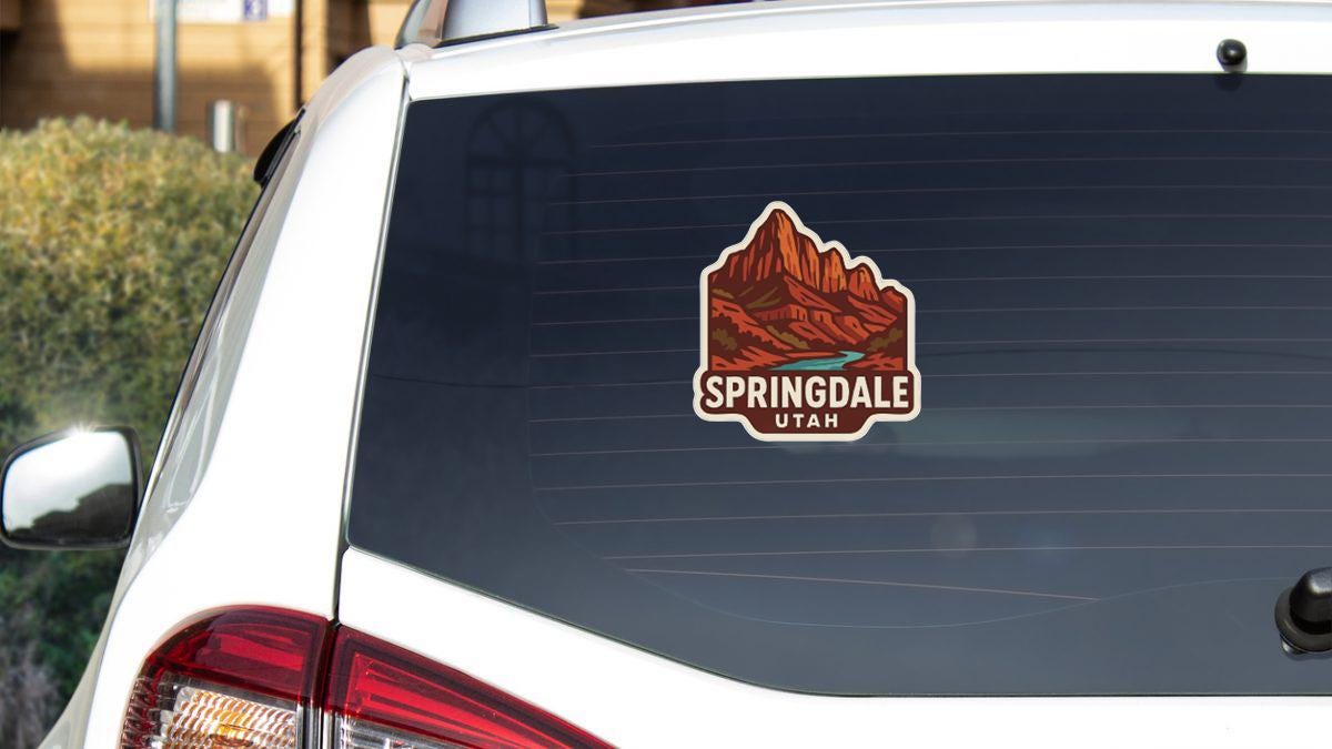 A sticker on the rear window of a white vehicle, depicting a mountain range with the text "Springdale Utah" below it.