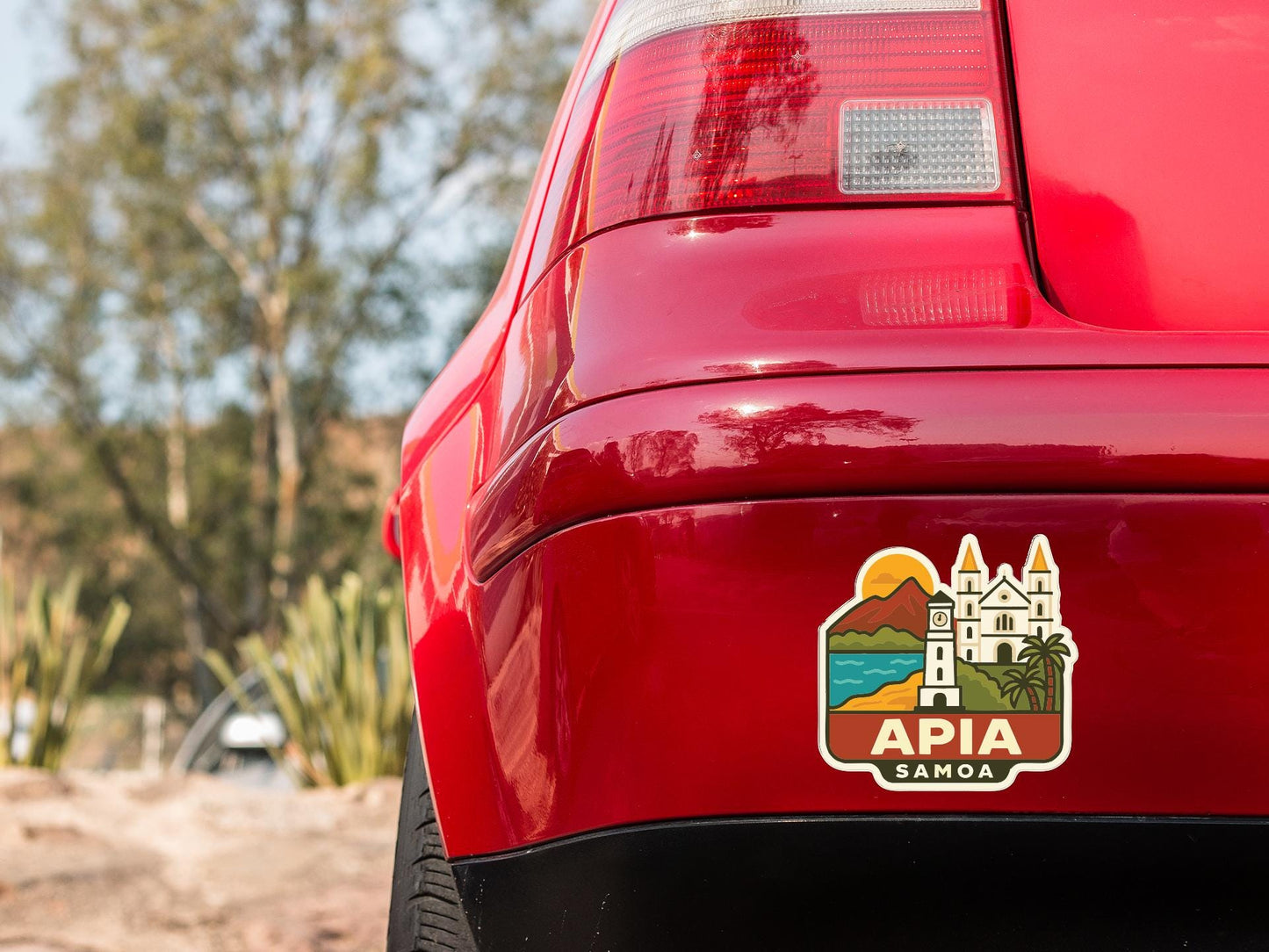 the rear end of a red car with a sticker on the trunk that features a tropical island and palm trees, along with the text "APIA SAMOA".
