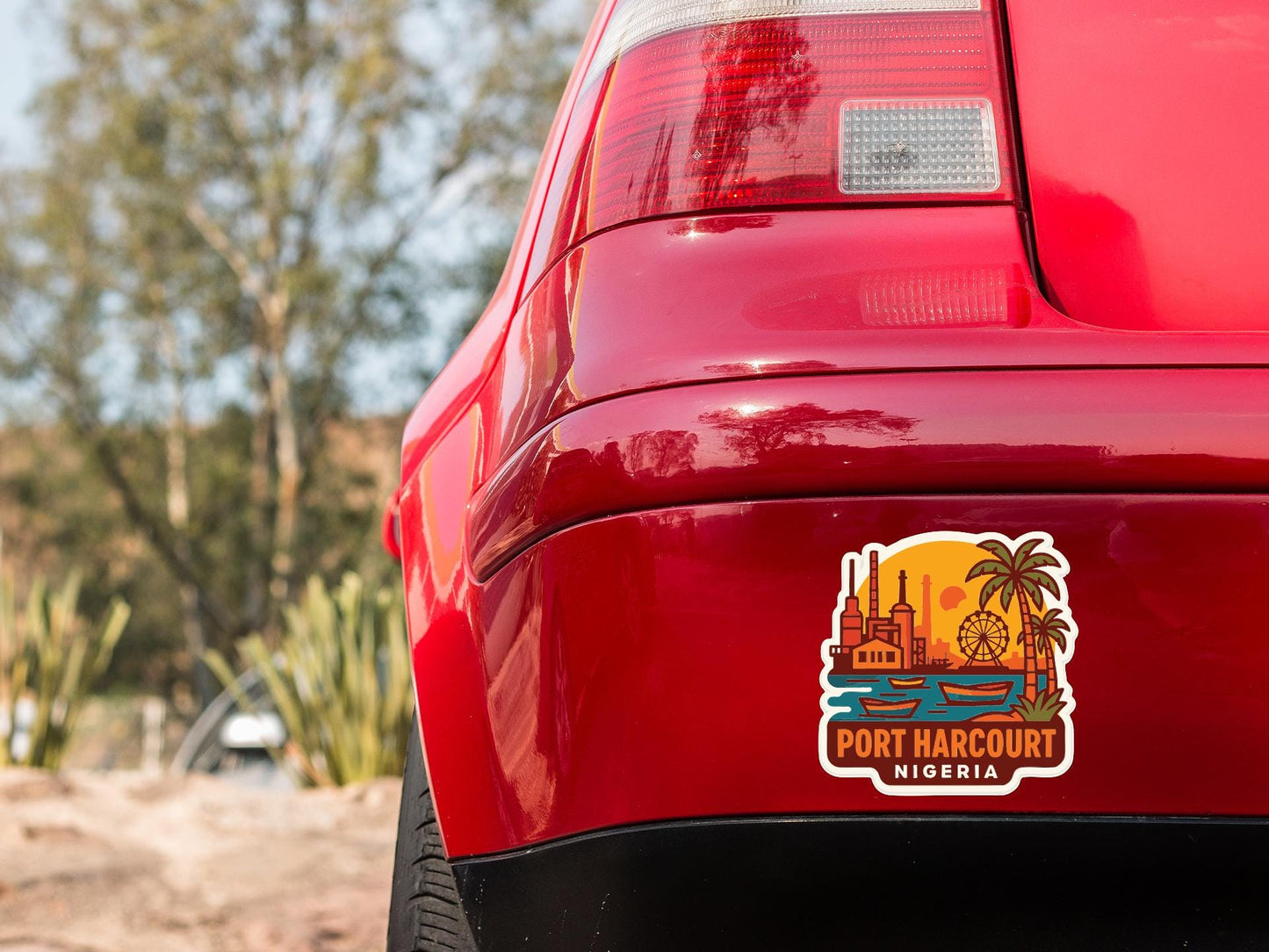 the rear end of a red car with a sticker on the trunk that says "PORT HARcourt NIGERIA".