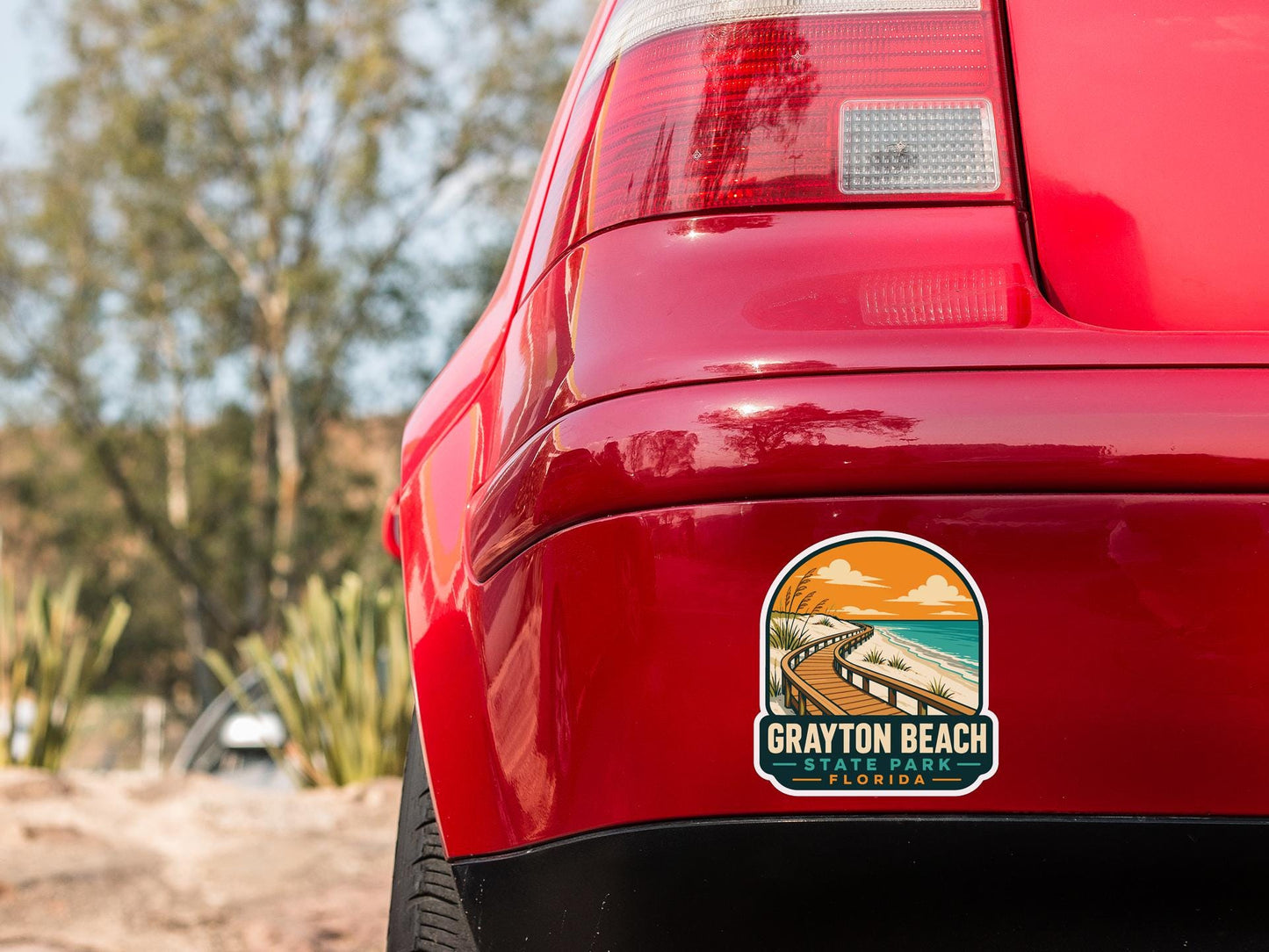 the rear end of a red car with a sticker on the back window that says "Grayson Beach State Park, Florida".