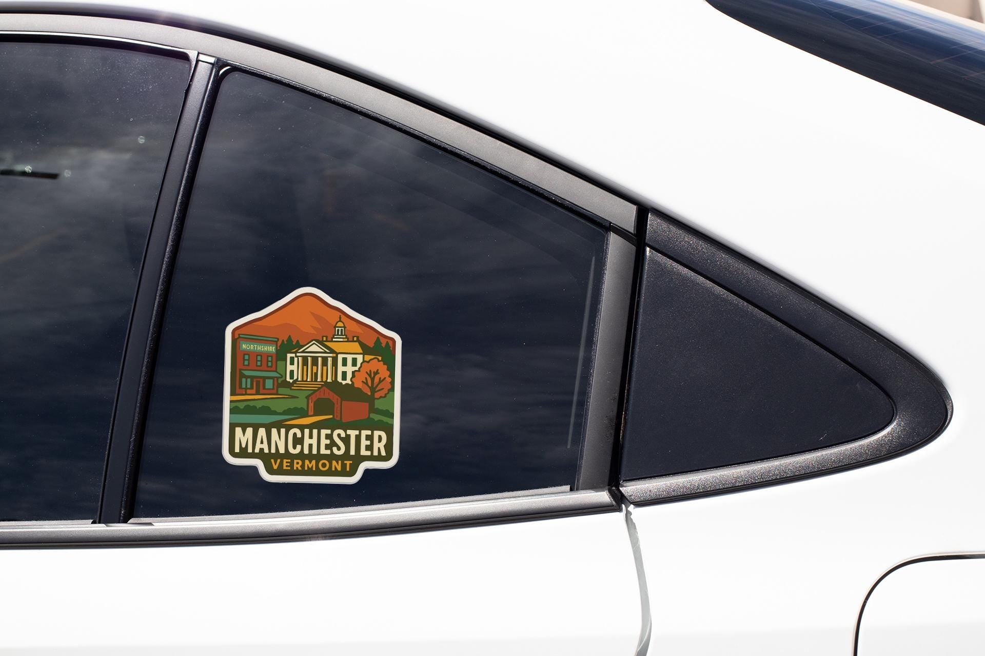A sticker on the side of a car window, depicting a scenic view of Manchester, Vermont.