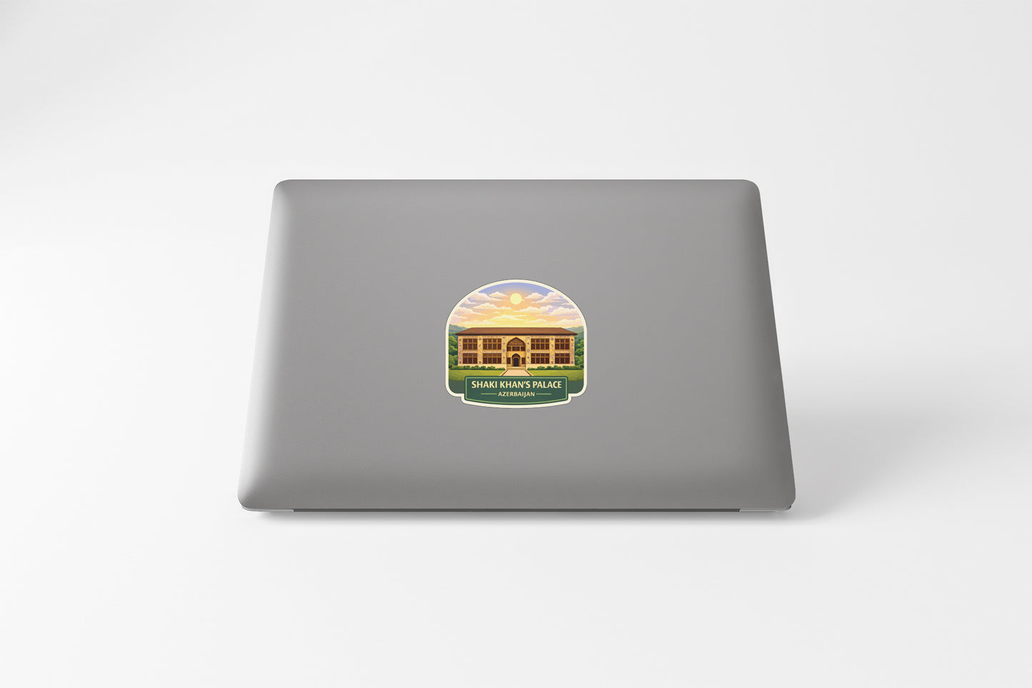 A sticker on the back of a laptop, depicting a building with a sunset in the background.