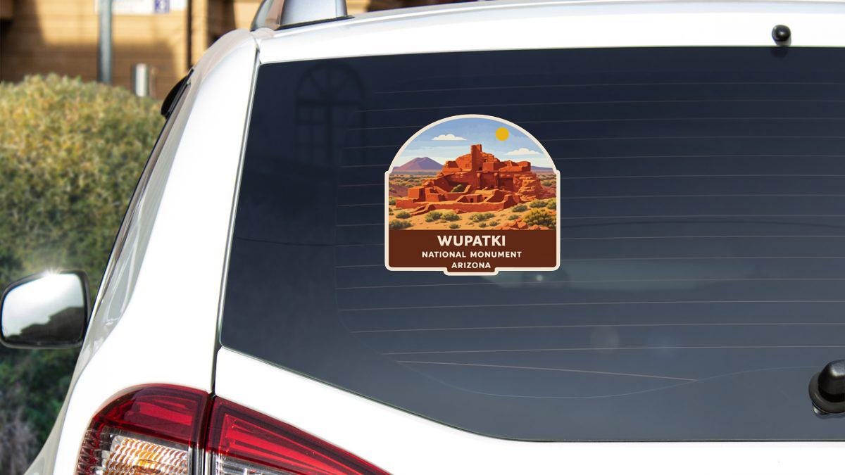 A sticker on the rear window of a car that says "WUPATKI NATIONAL MONUMENT ARIZONA" and features an illustration of the Wupatki National Monument in Arizona.