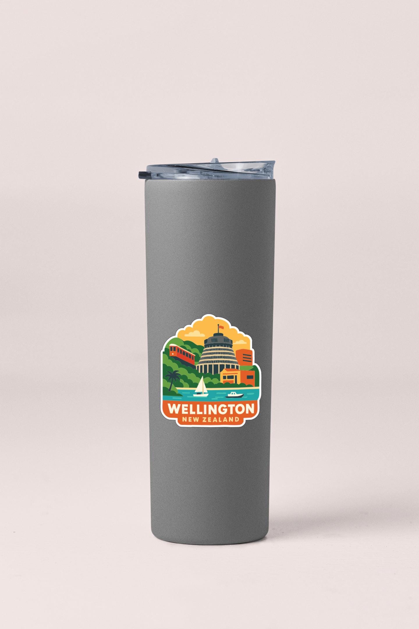 A gray insulated tumbler with a printed sticker depicting a cityscape and the text " Wellington New Zealand".