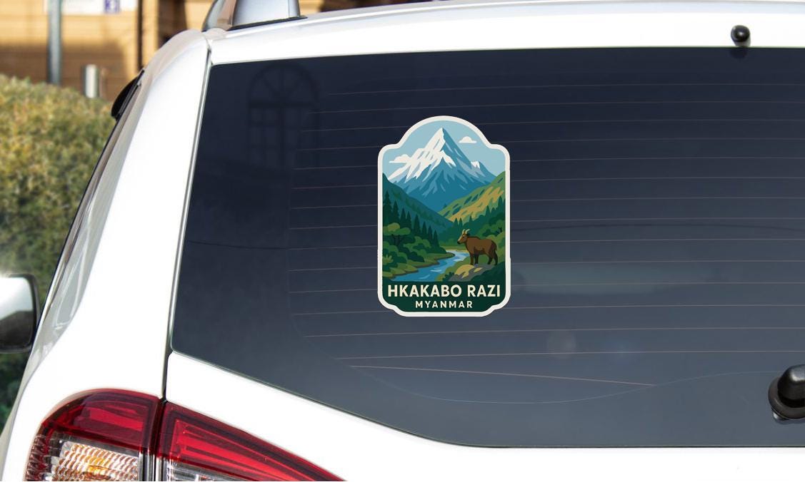 A sticker on the rear window of a car, depicting a mountain landscape with a bear in the foreground.