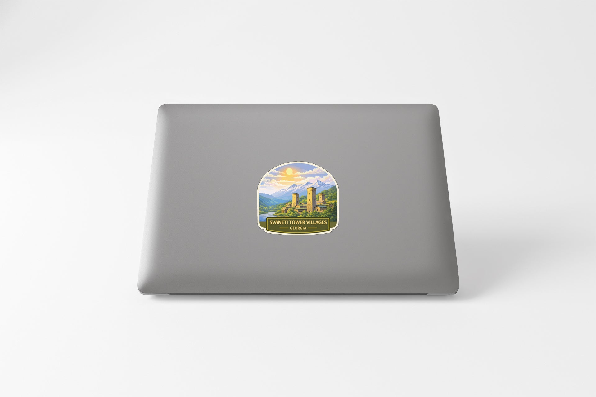 A sticker on the back of a laptop, depicting a scenic landscape with mountains and a lake.