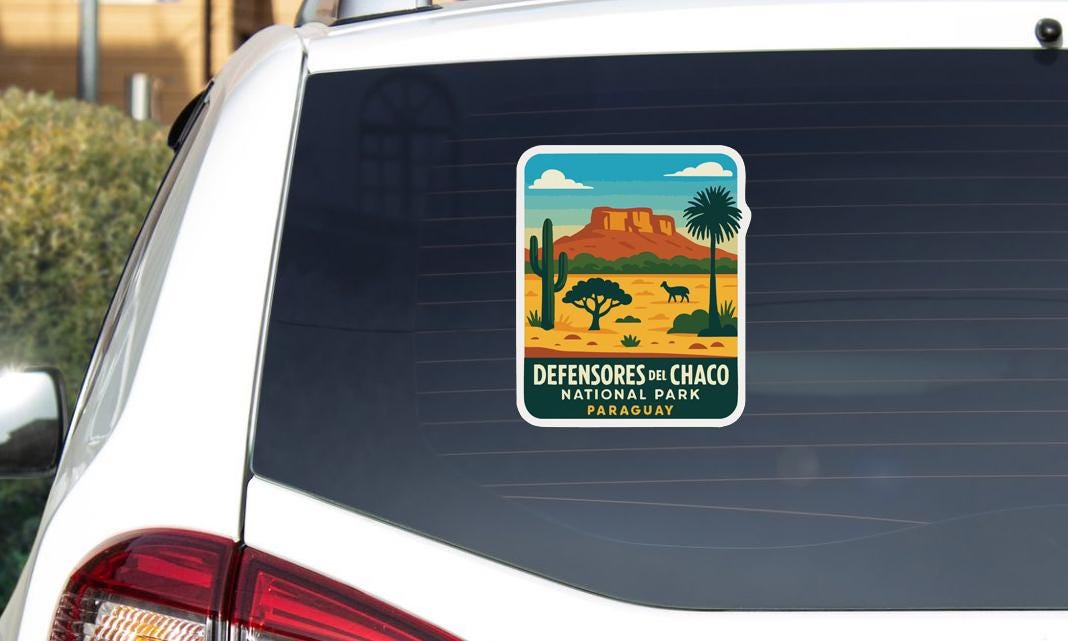 A sticker on the rear window of a car, depicting a desert landscape with mountains, cacti, and a lone figure.