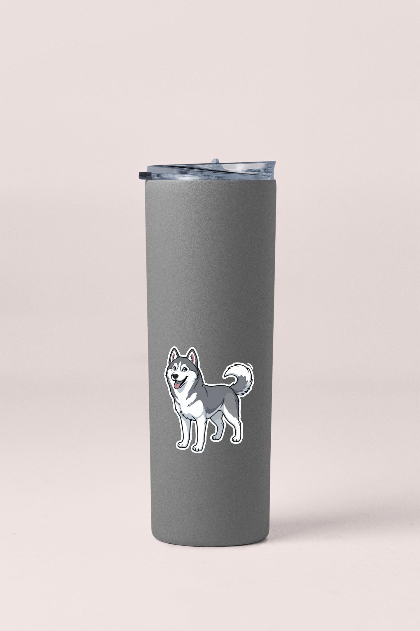 A gray insulated tumbler with a sticker of a husky dog on it.