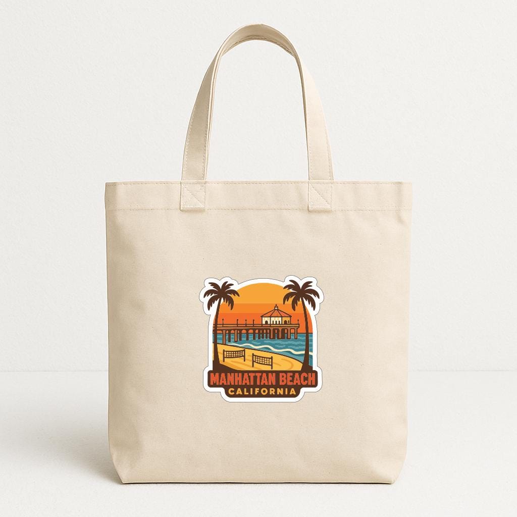 A beige tote bag with a sticker depicting the Manhattan Beach, California beach scene.