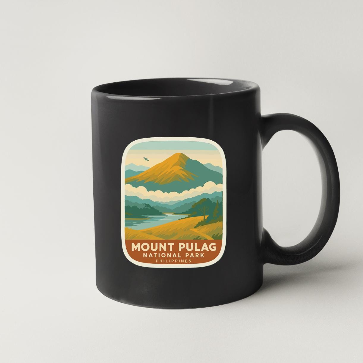 A black coffee mug with a graphic design depicting a mountain landscape and the text "Mount Pulag National Park" printed on it.