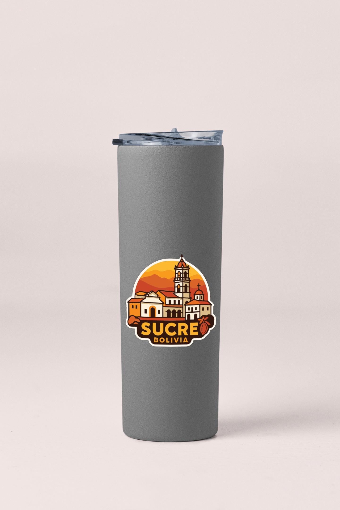 A gray insulated tumbler with a graphic design featuring a cityscape and the text "Sucre Bolivia" printed on it.
