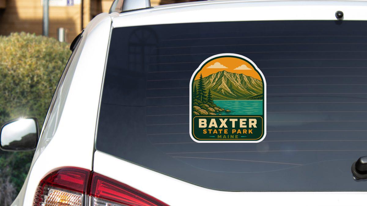 A sticker on the rear window of a white car, depicting a scenic mountain landscape with a lake.