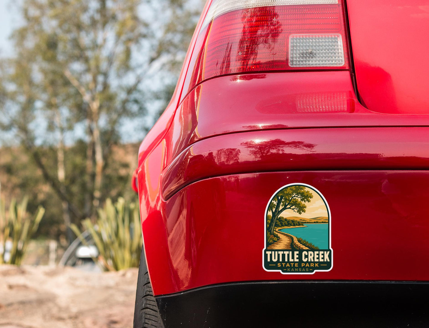 the rear end of a red car with a sticker on the trunk that says "Tuttle Creek".