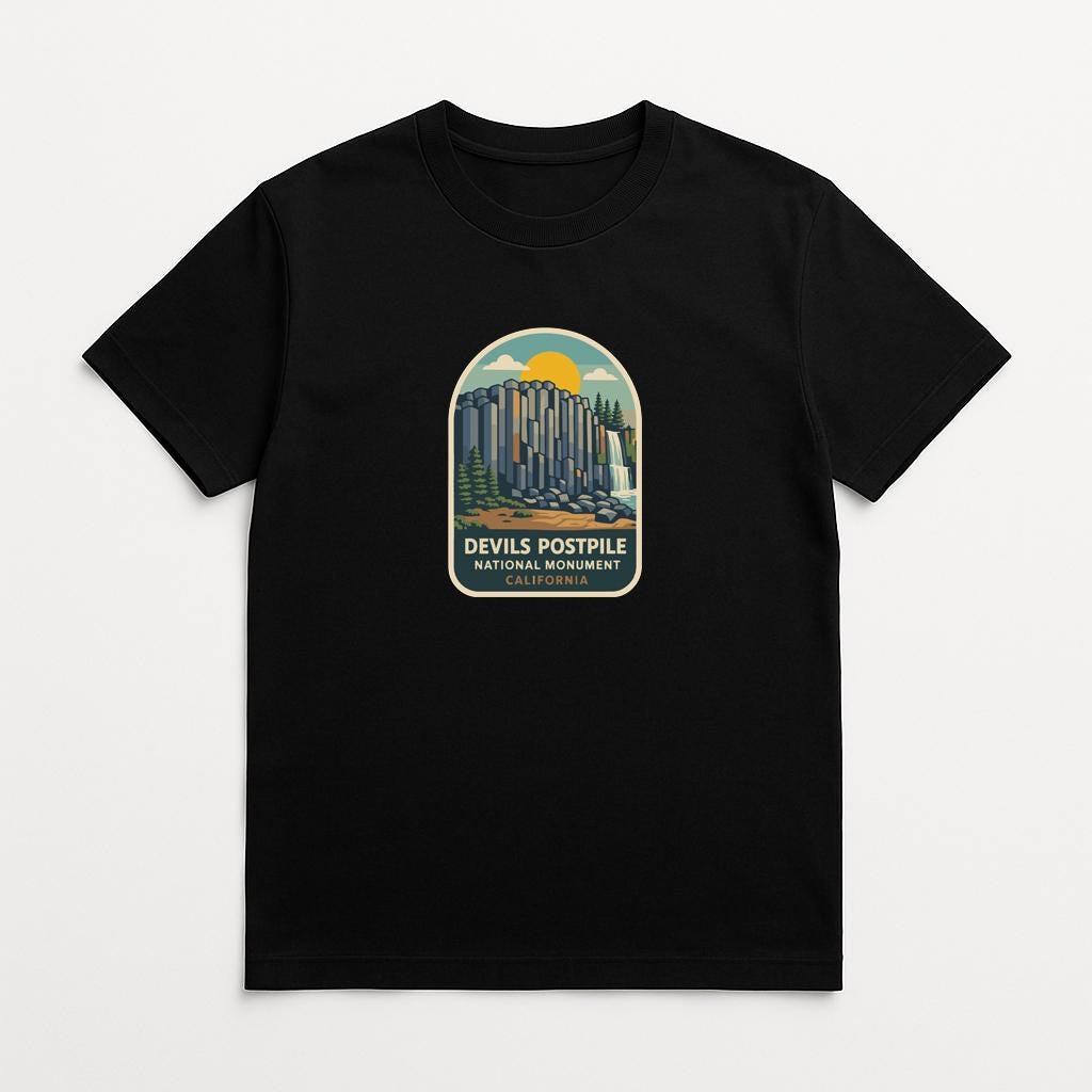 A black t-shirt with a graphic design depicting a mountain range and the text "Devils Postpile National Monument" printed on it.