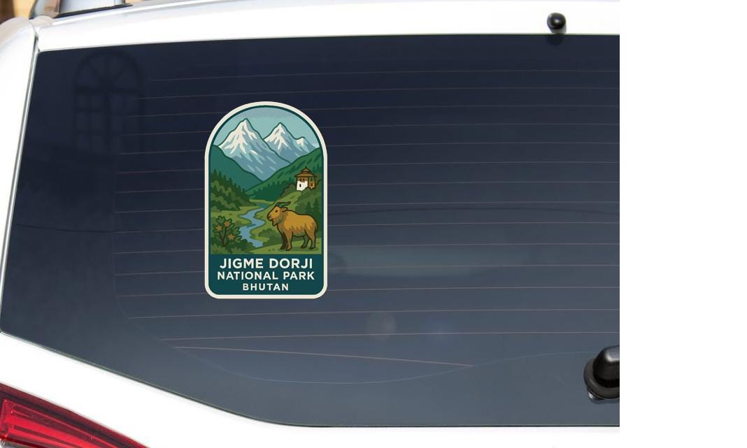A sticker on the rear window of a vehicle, depicting a mountain landscape with a person and a goat.
