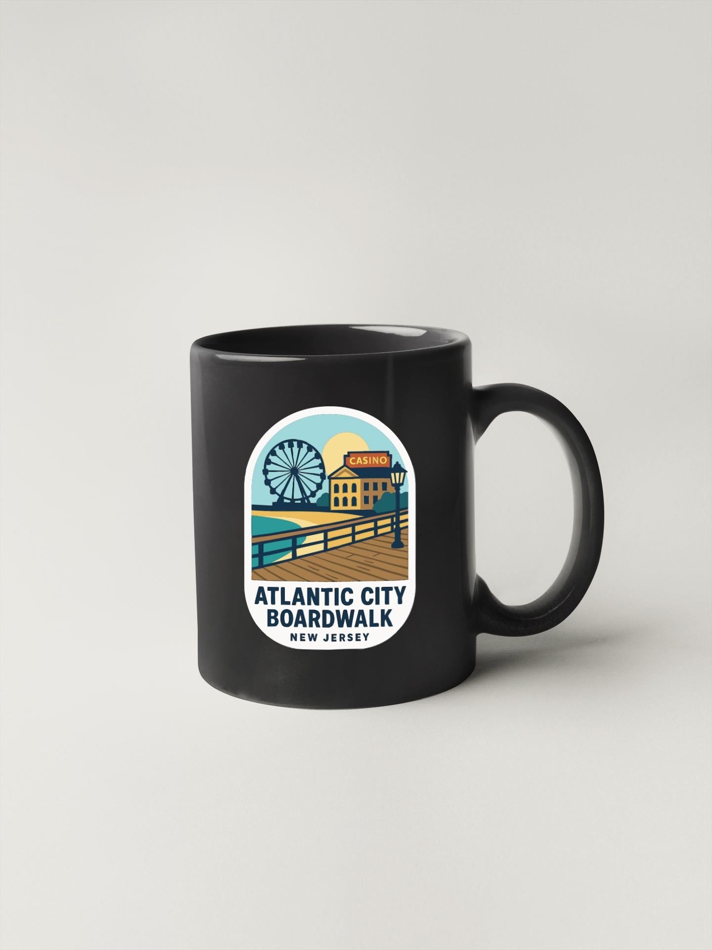 A black coffee mug with a sticker depicting a boardwalk scene and the text "Atlantic City Boardwalk New Jersey".