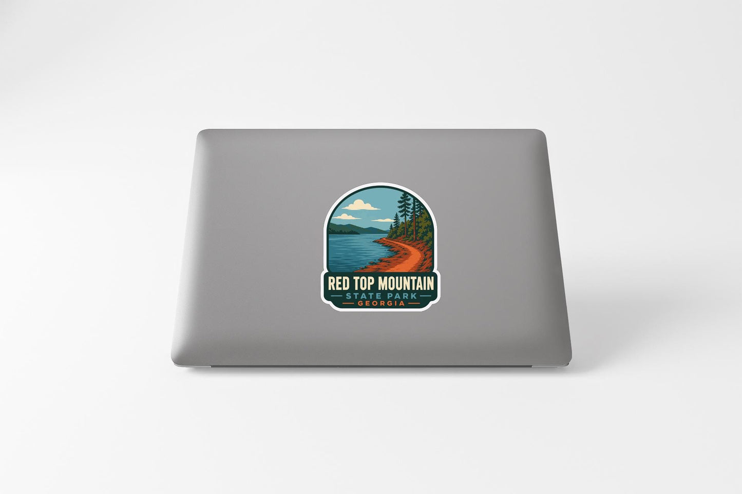 a sticker on a laptop that depicts a scenic landscape with a lake, mountains, and trees.