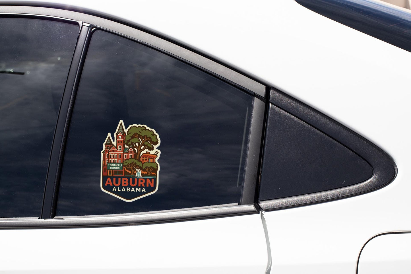 A car window with a sticker depicting a building and the text "Auburn Alabama" on it.
