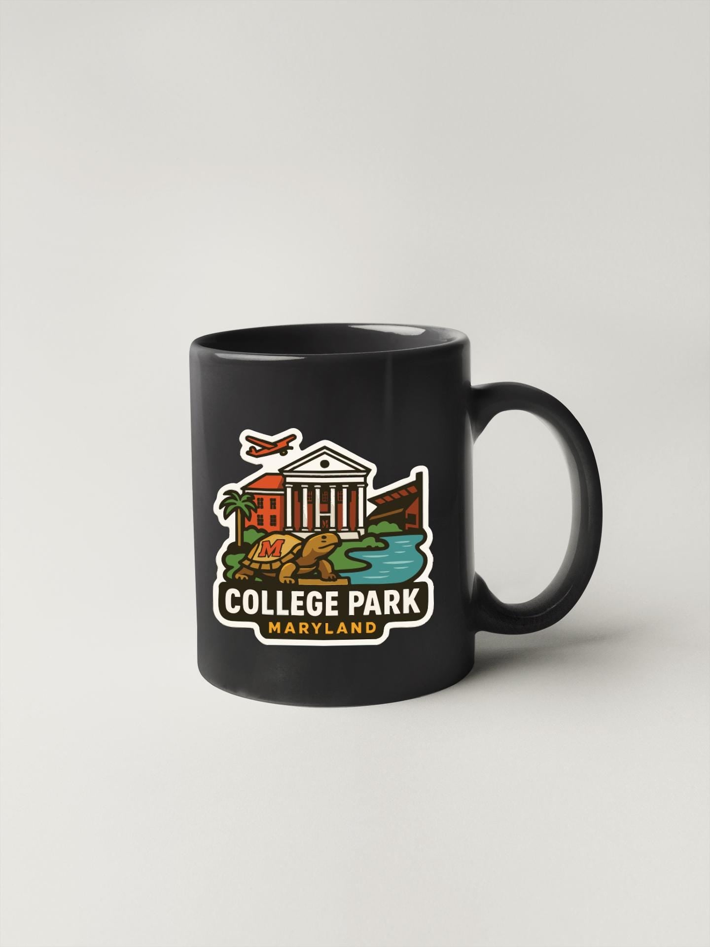 A black coffee mug with a colorful illustration of a college park in Maryland.