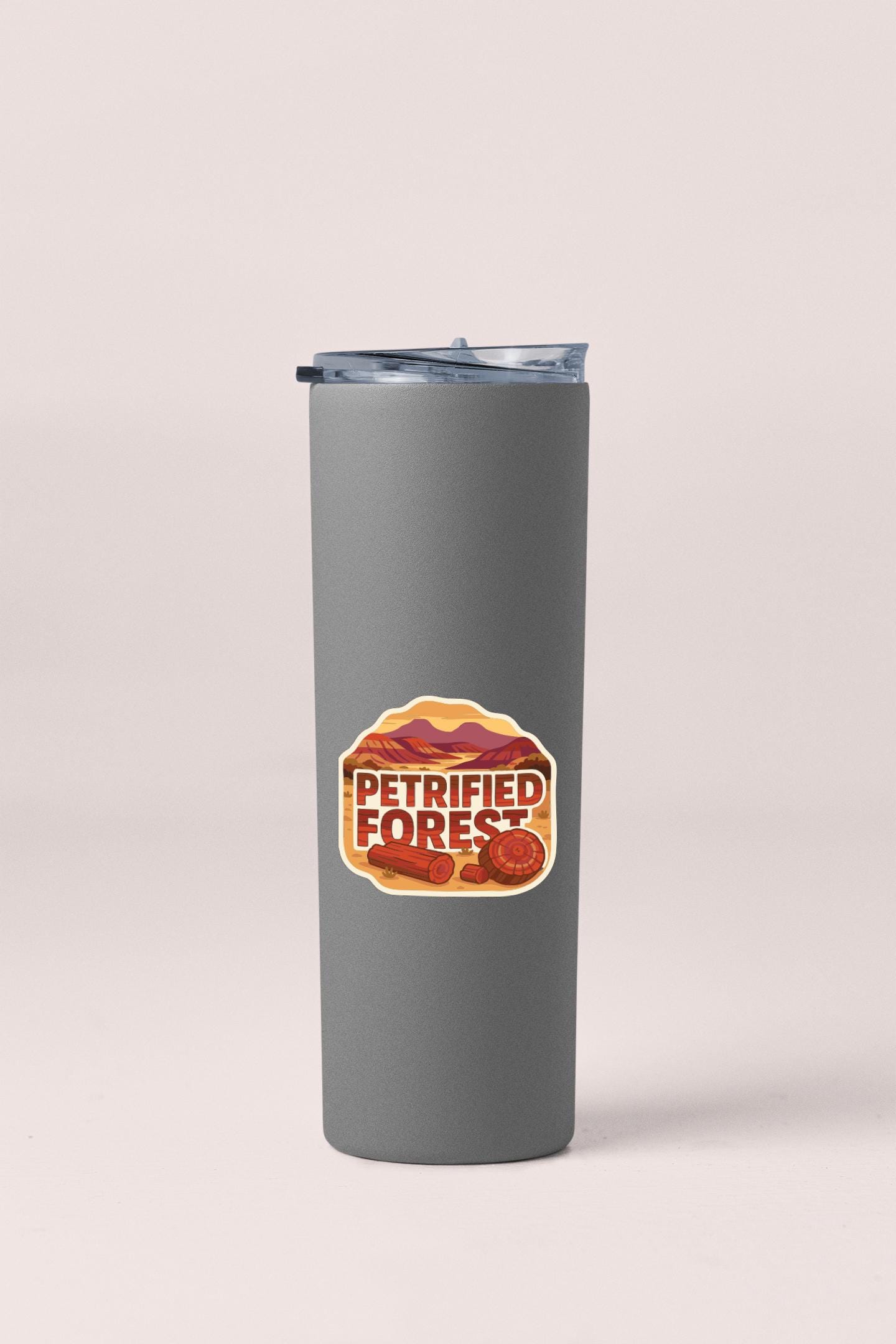 A gray insulated tumbler with a lid and a sticker on it.