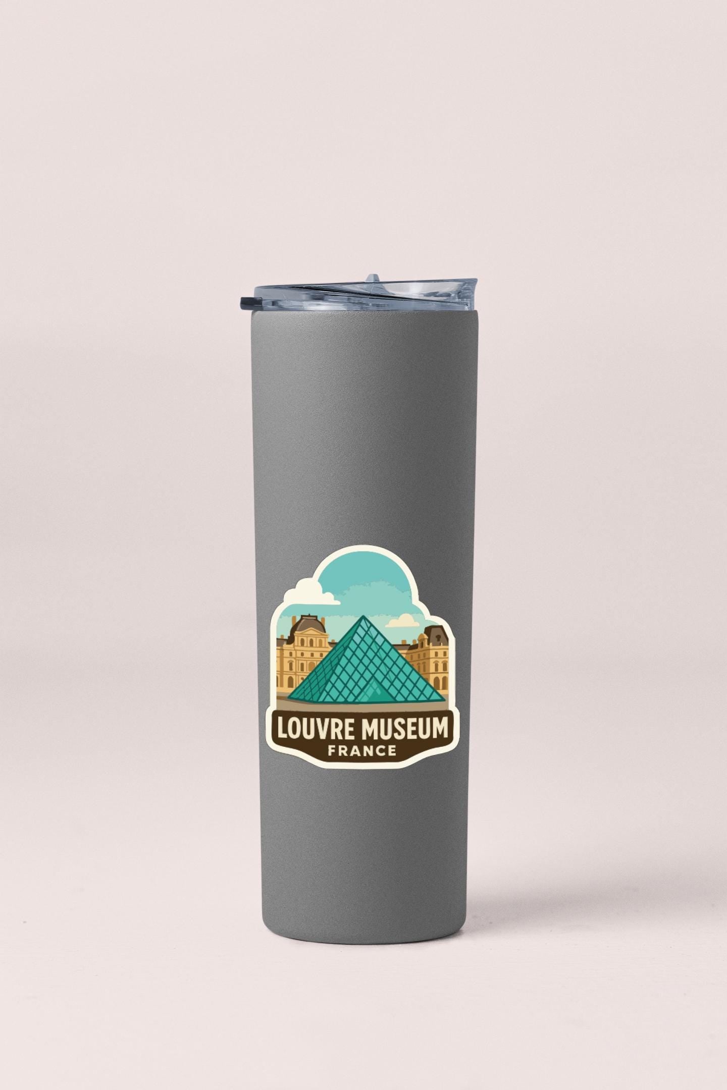 A gray insulated tumbler with a sticker featuring the Louvre Museum in Paris, France.