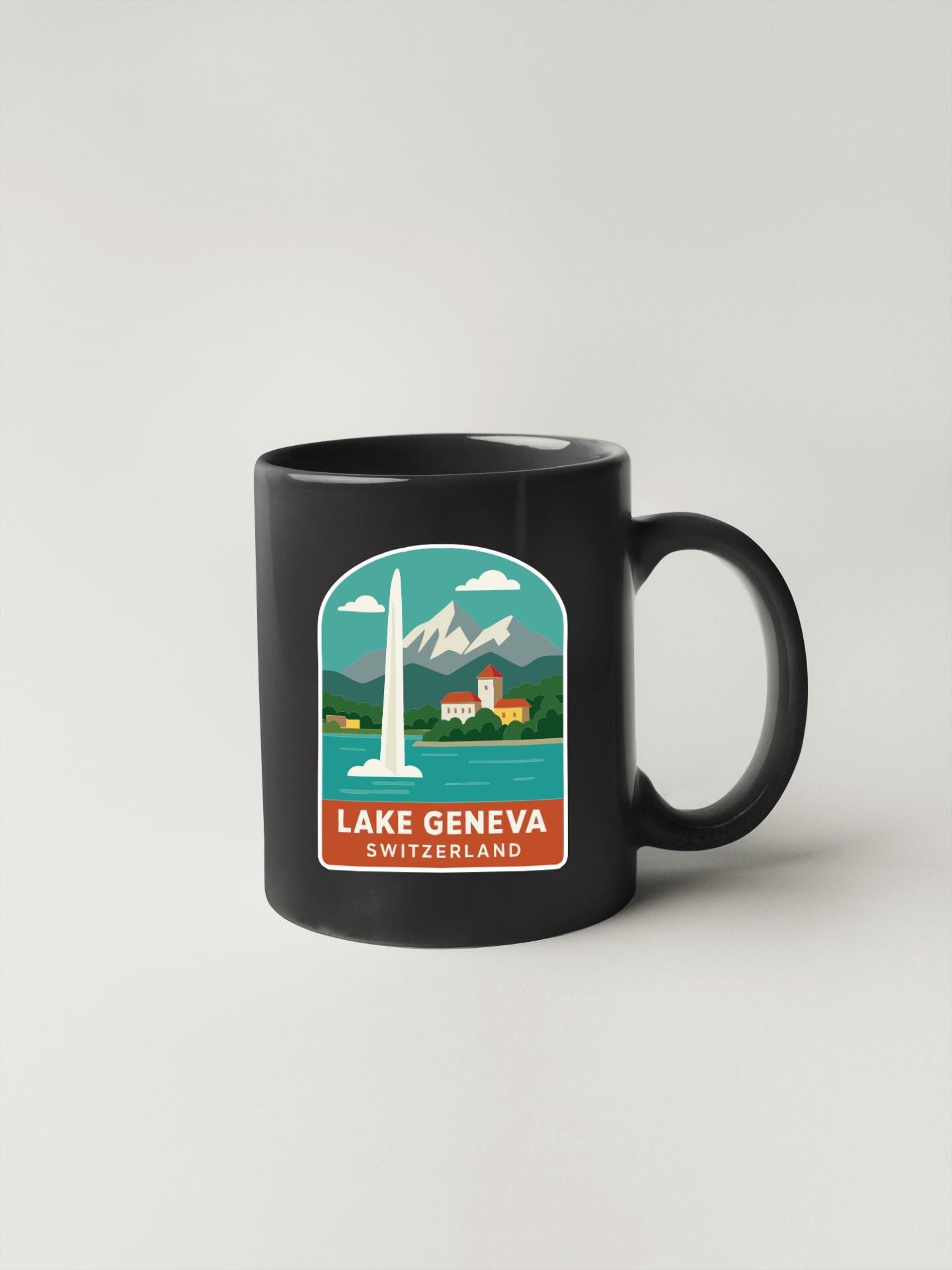 A black coffee mug with a sticker depicting Lake Geneva, Switzerland, featuring a tall tower and mountains in the background.