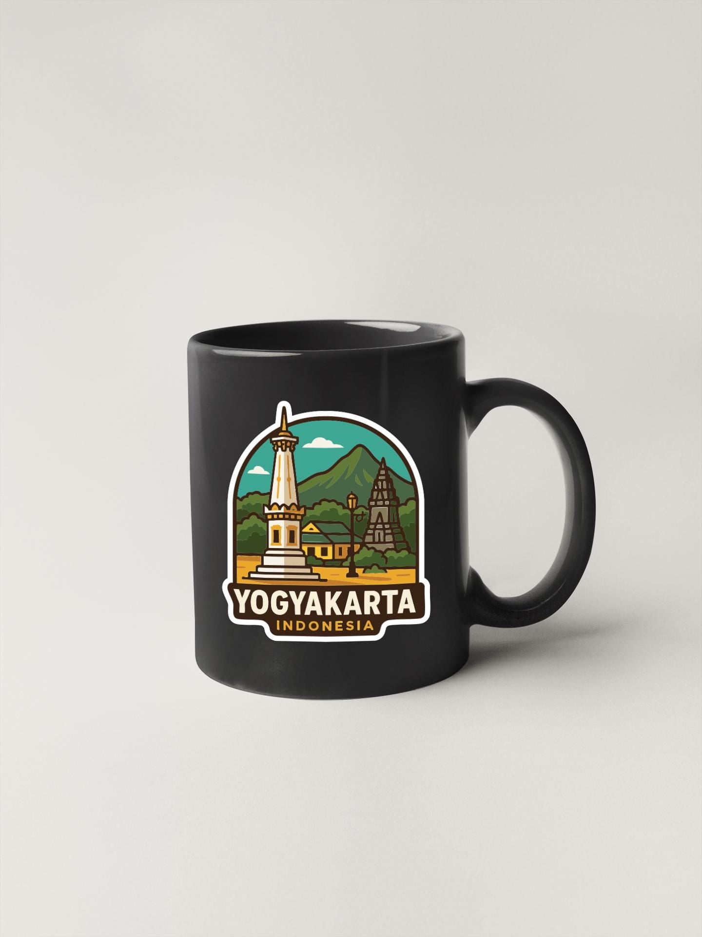 A black coffee mug with a sticker depicting the Yogyakarta, Indonesia landmark.