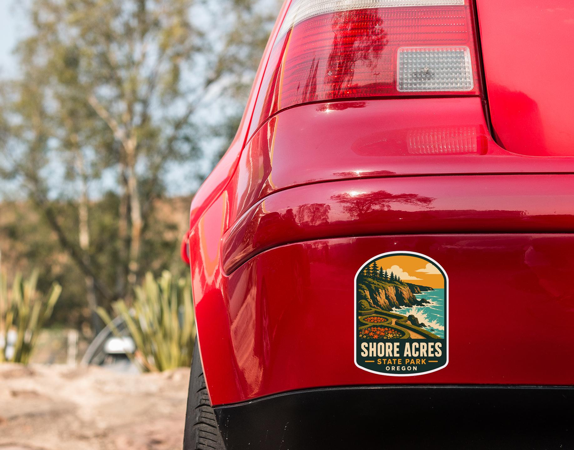 the rear end of a red car with a sticker on the back window that says "SHORE ACRES STATE PARK OREGON".