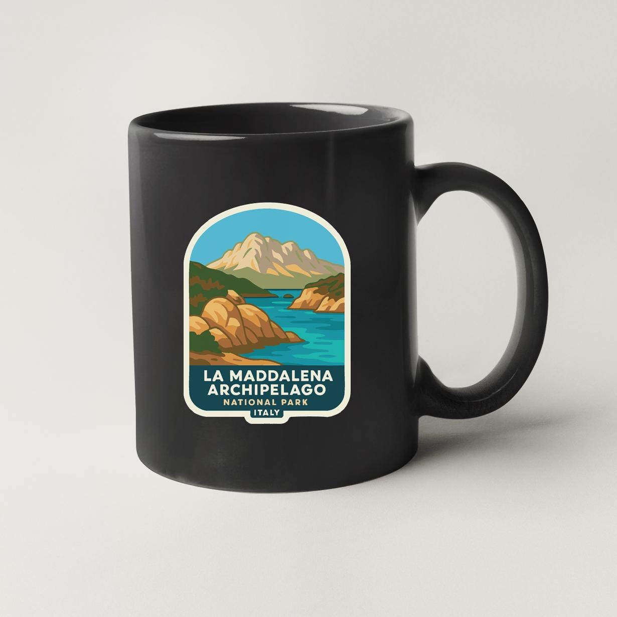 A black coffee mug with a label that features an illustration of a mountainous landscape with a lake and mountains.