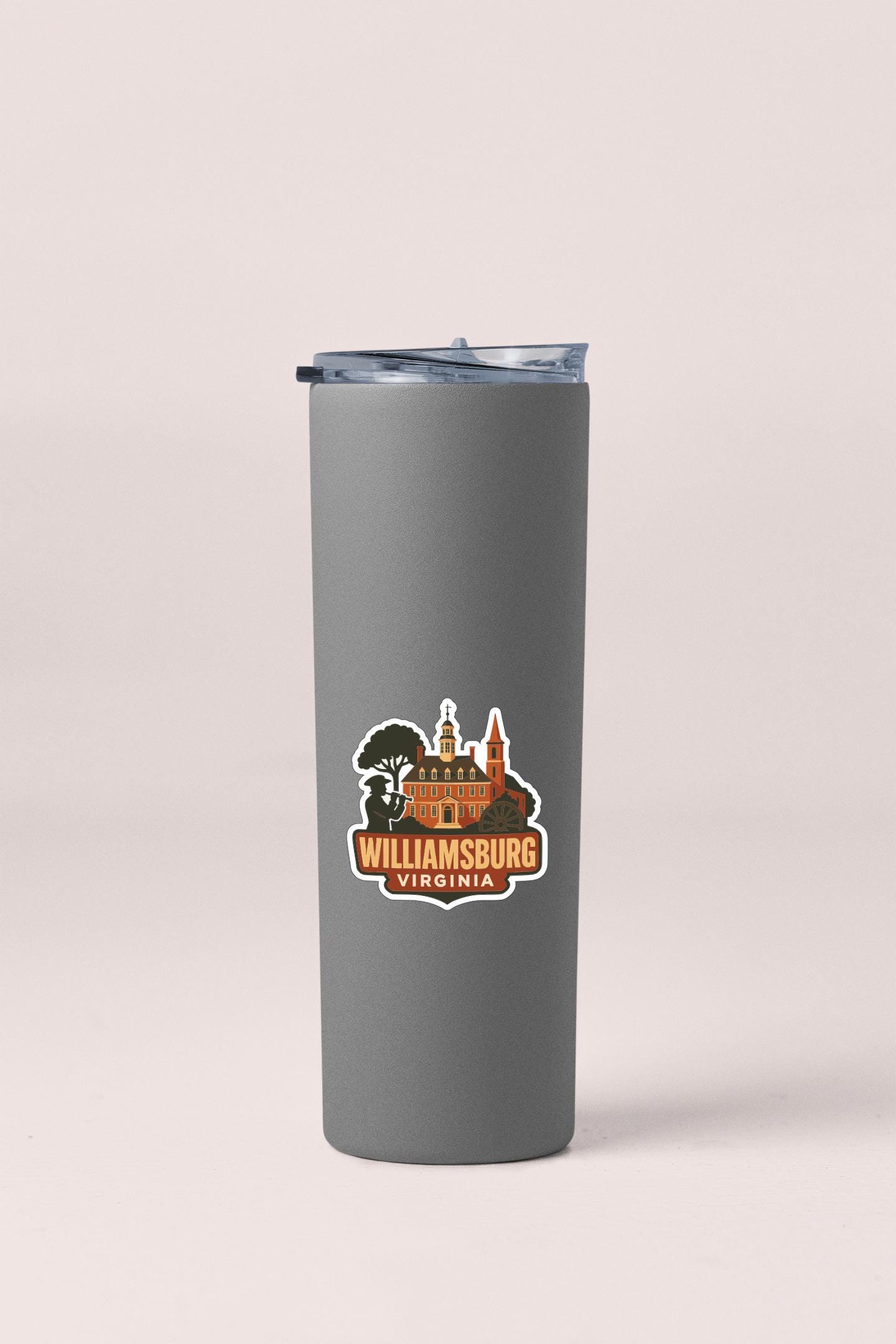 A gray insulated tumbler with a sticker depicting a landmark, likely Williamsburg, Virginia.