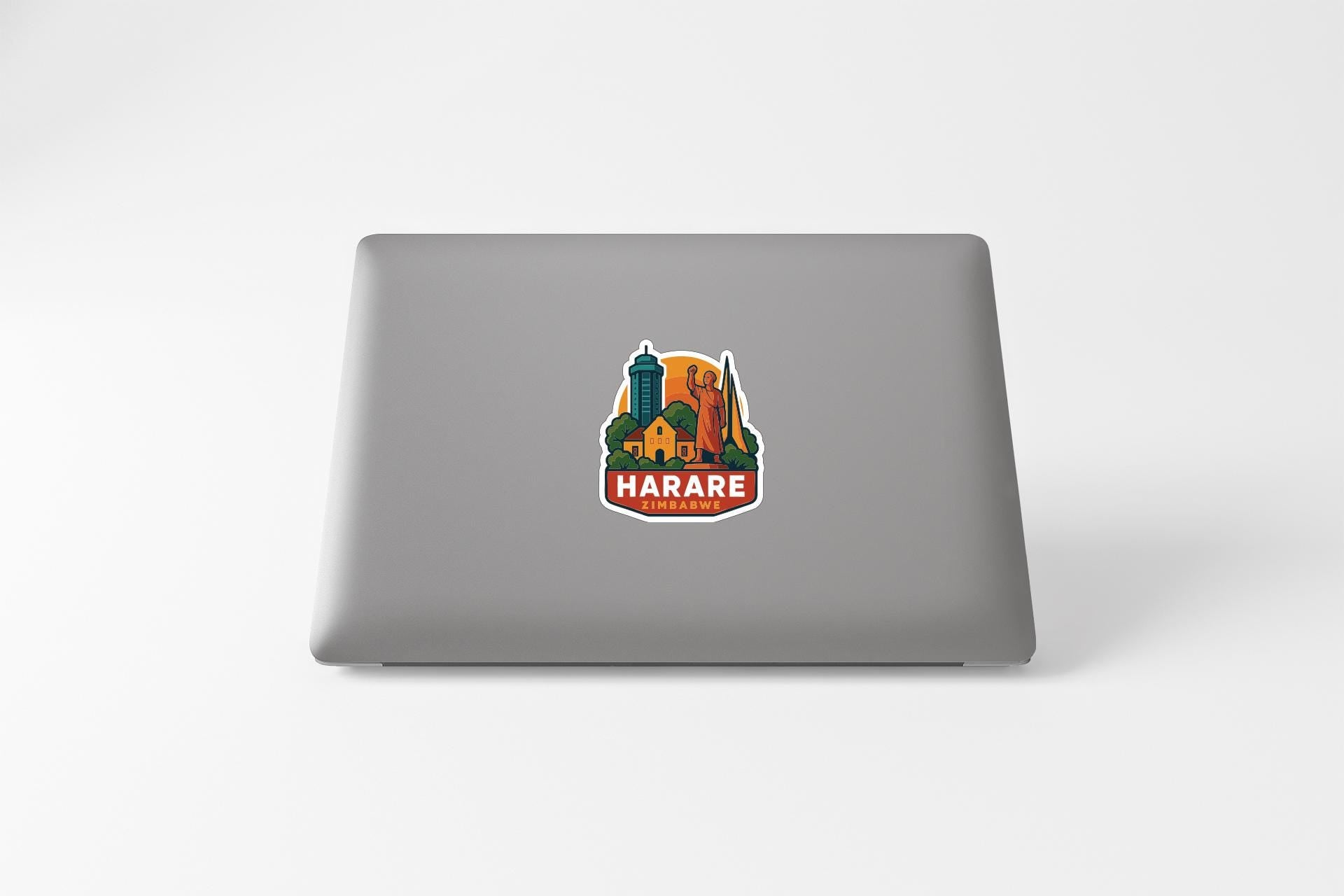 a sticker with a colorful illustration of a cityscape and the text "HARARE" on a laptop.