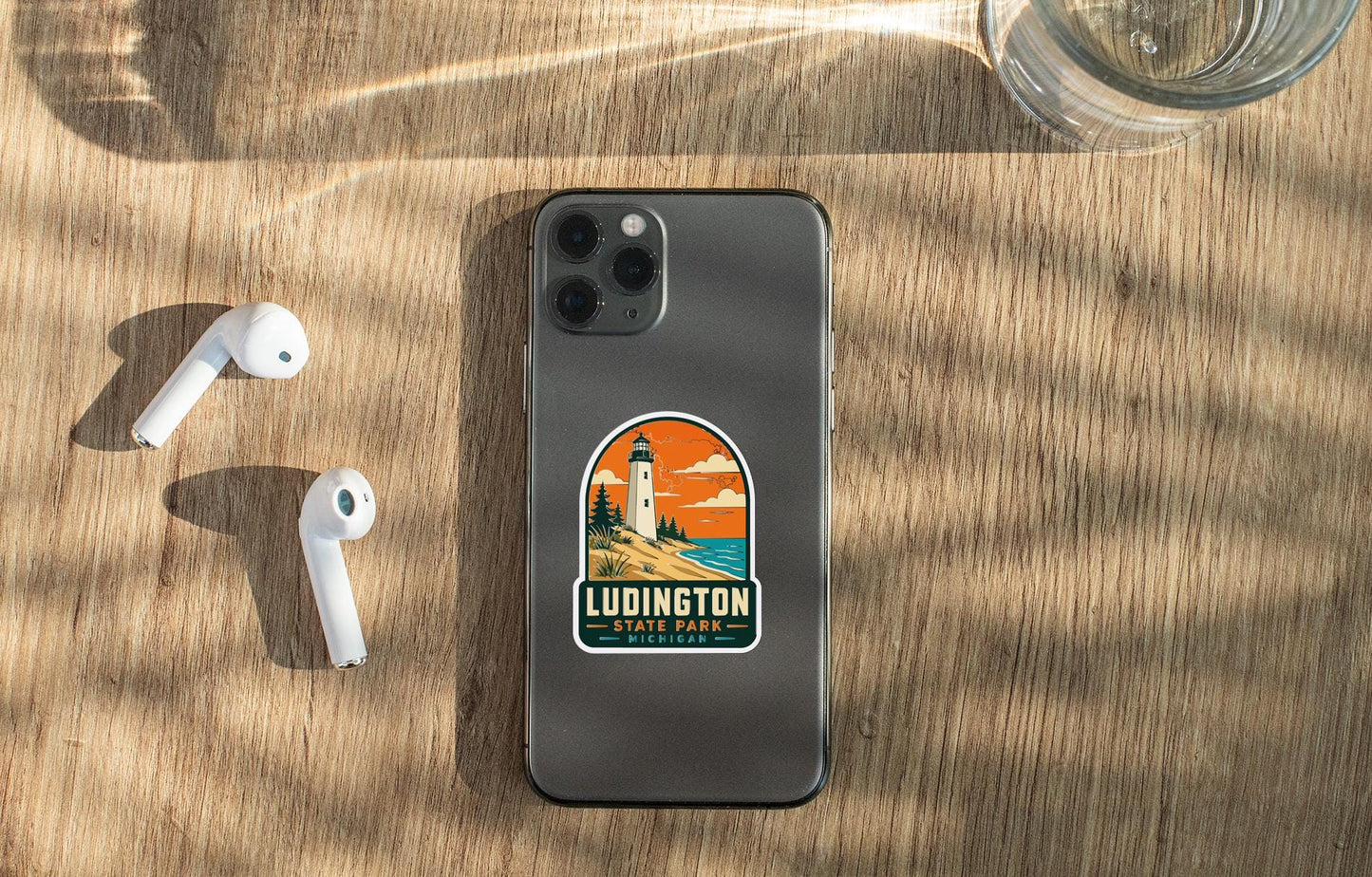 a smartphone with a sticker on the back, placed on a wooden surface alongside a pair of white earbuds and a glass of water.