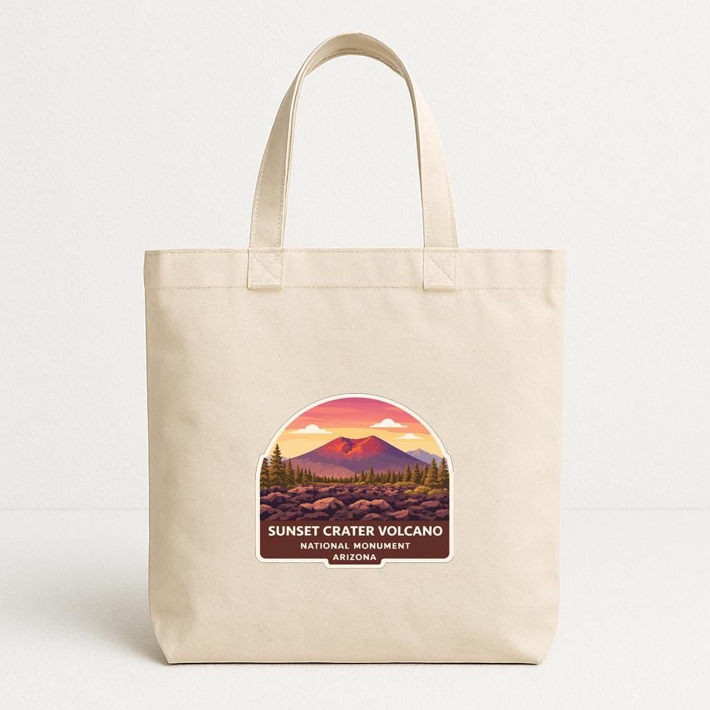 A beige tote bag with a graphic design depicting a scenic landscape featuring a mountain range and a sunset.