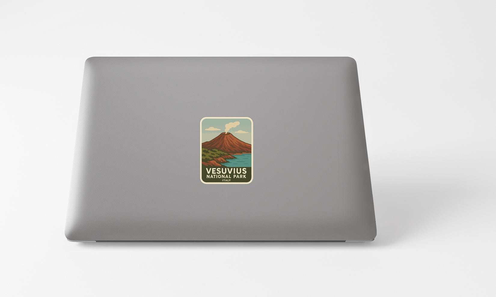 A sticker on the back of a laptop, depicting a mountain landscape with a volcano.
