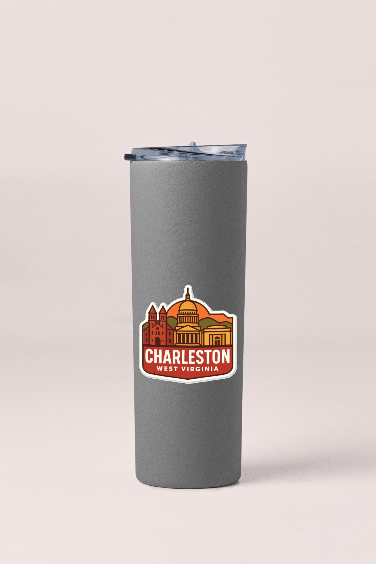 A gray insulated tumbler with a sticker depicting the Charleston, West Virginia skyline.