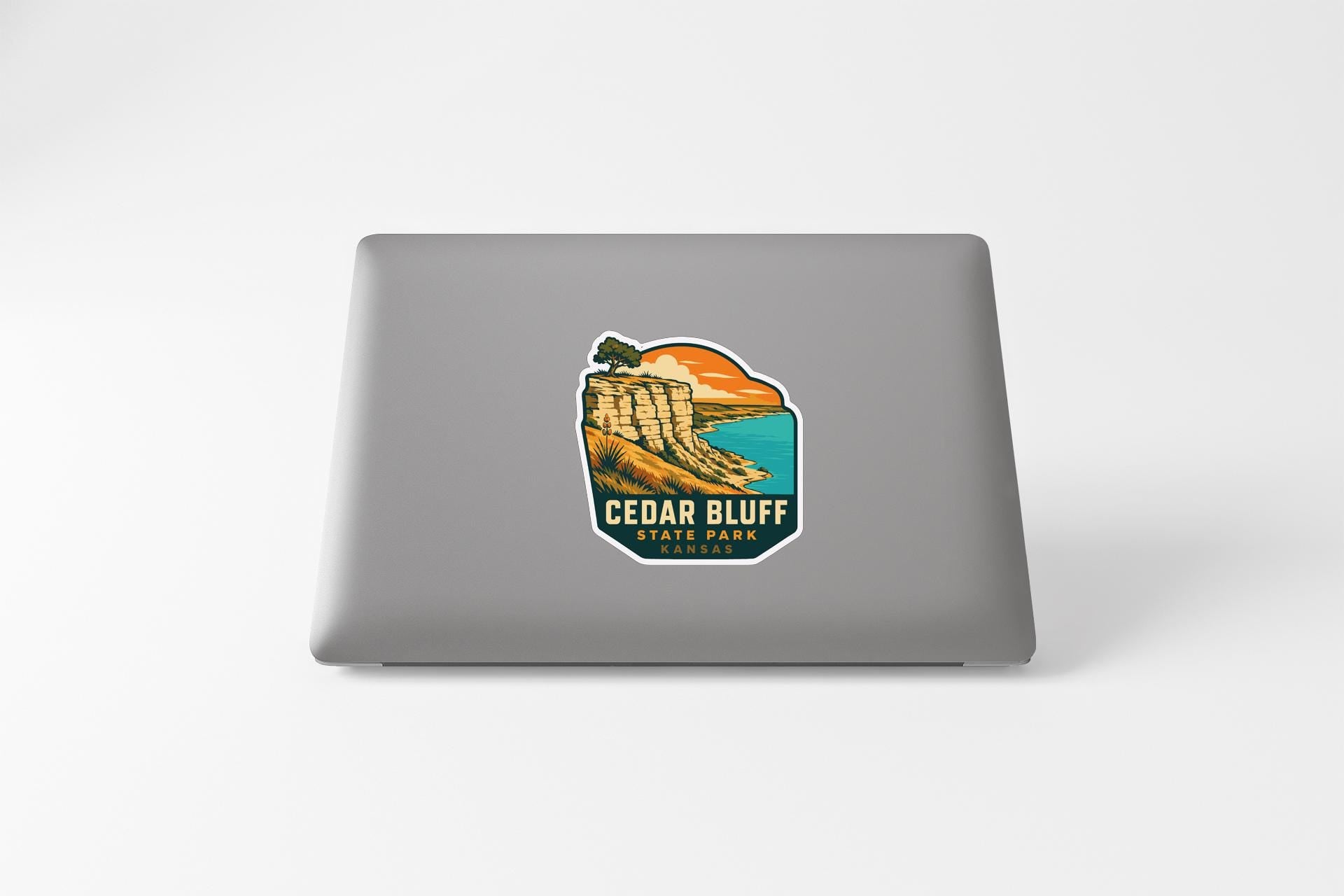 a sticker or decal of a scenic landscape with a cliff overlooking a body of water, likely representing Cedar Bluff State Park.