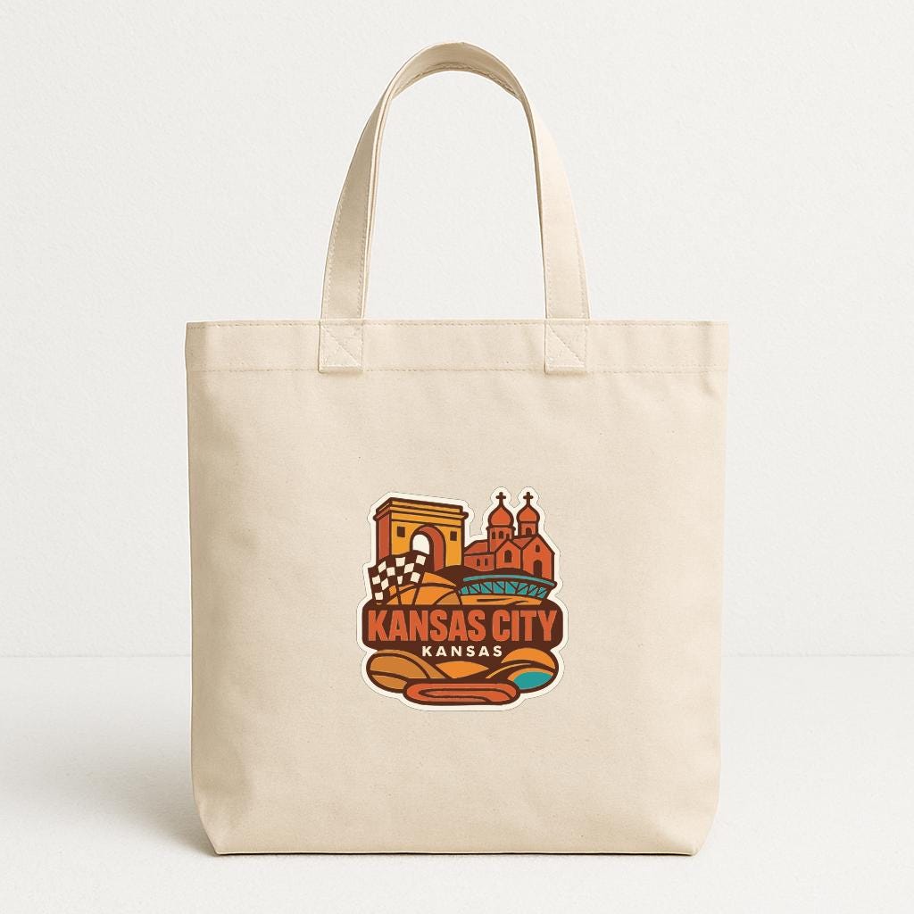 A beige tote bag with a colorful graphic design featuring a city skyline and the text "KANSAS CITY KANSAS" printed on it.