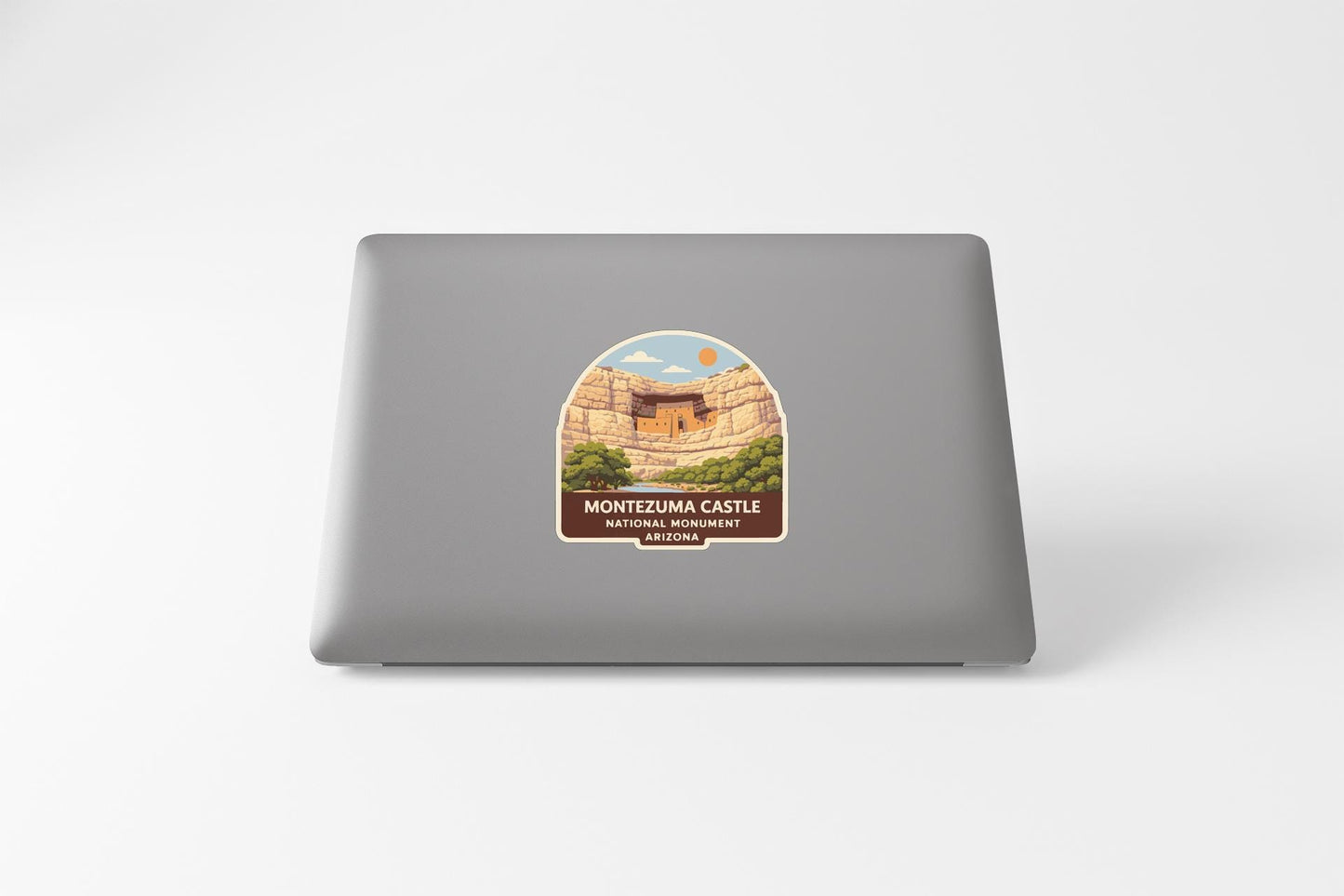a sticker on the back of a laptop, depicting a scenic landscape with a castle in the background.