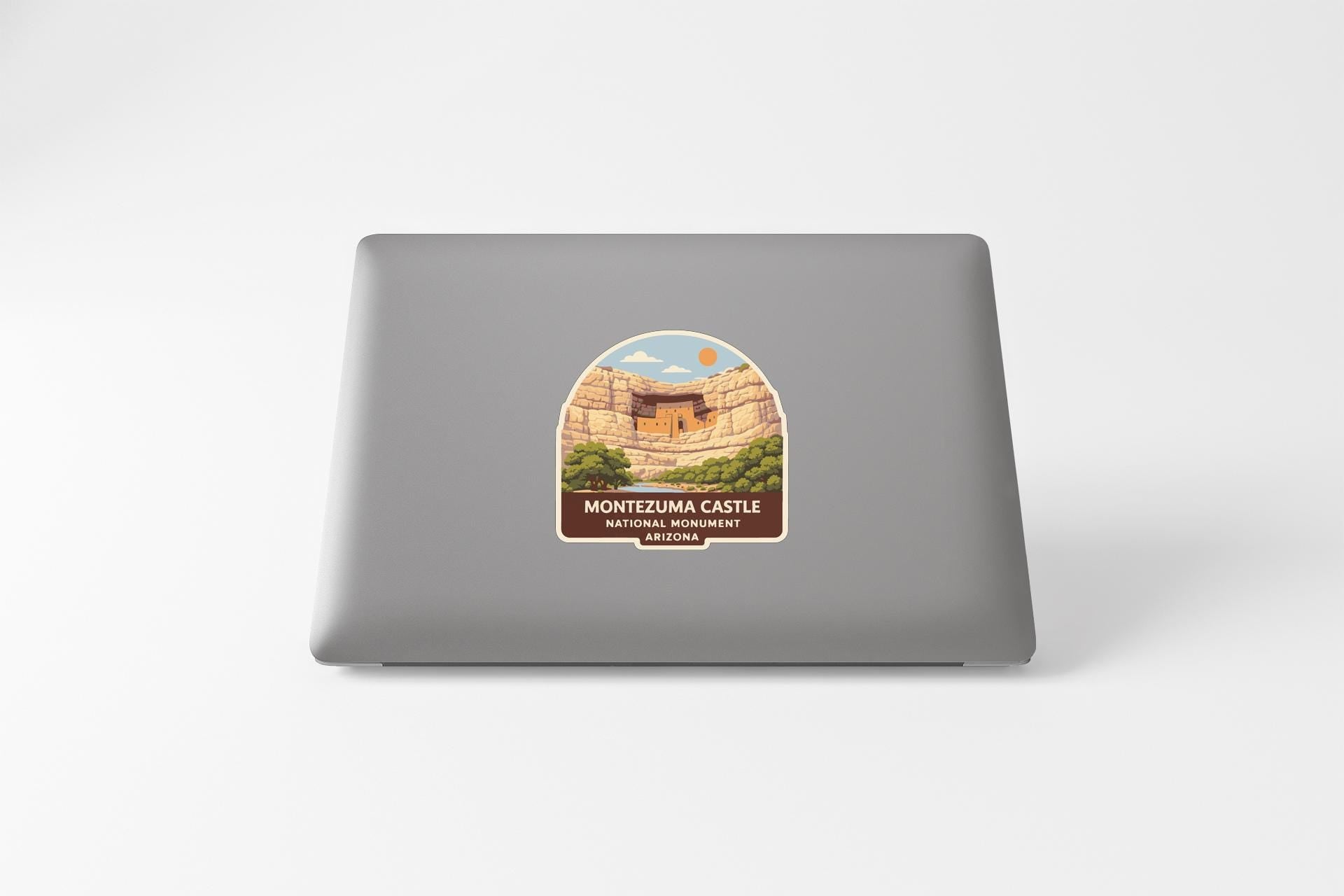 a sticker on the back of a laptop, depicting a scenic landscape with a castle in the background.