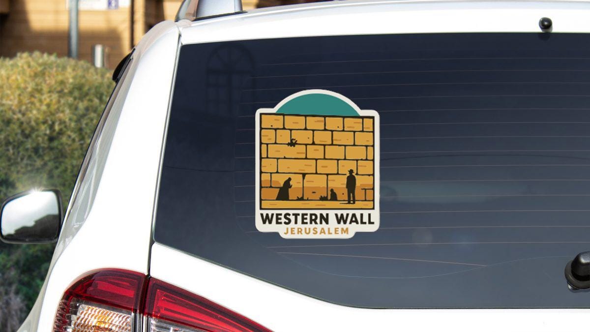 A sticker on the rear window of a white car, depicting a brick wall with a person and a dog in the foreground.