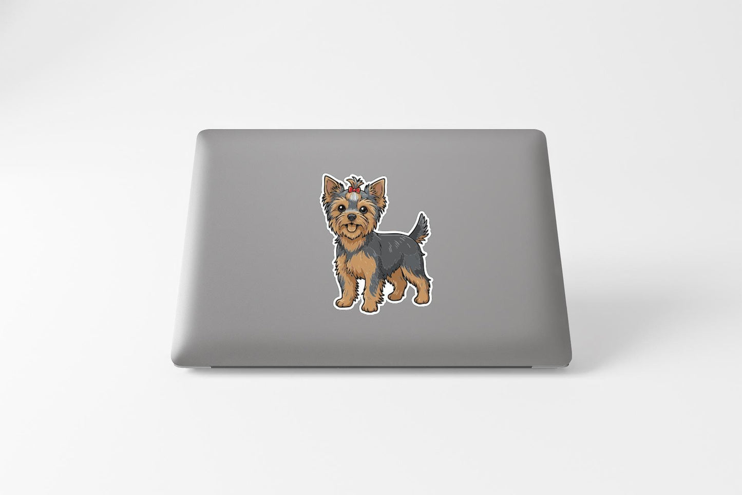 A cartoon image of a small dog, likely a Yorkshire Terrier, is displayed on the back of a laptop.