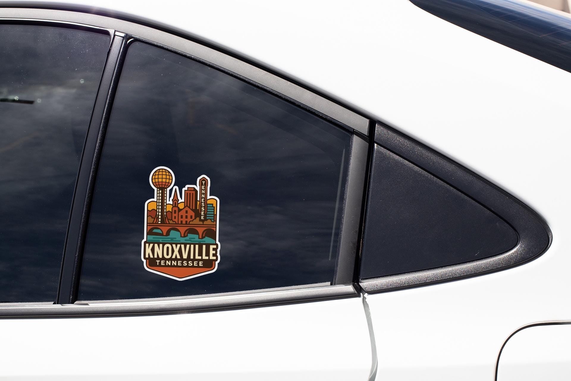 A car window with a sticker of Knoxville, Tennessee, featuring a cityscape and the text "KNOVILLE TENNESSEE".