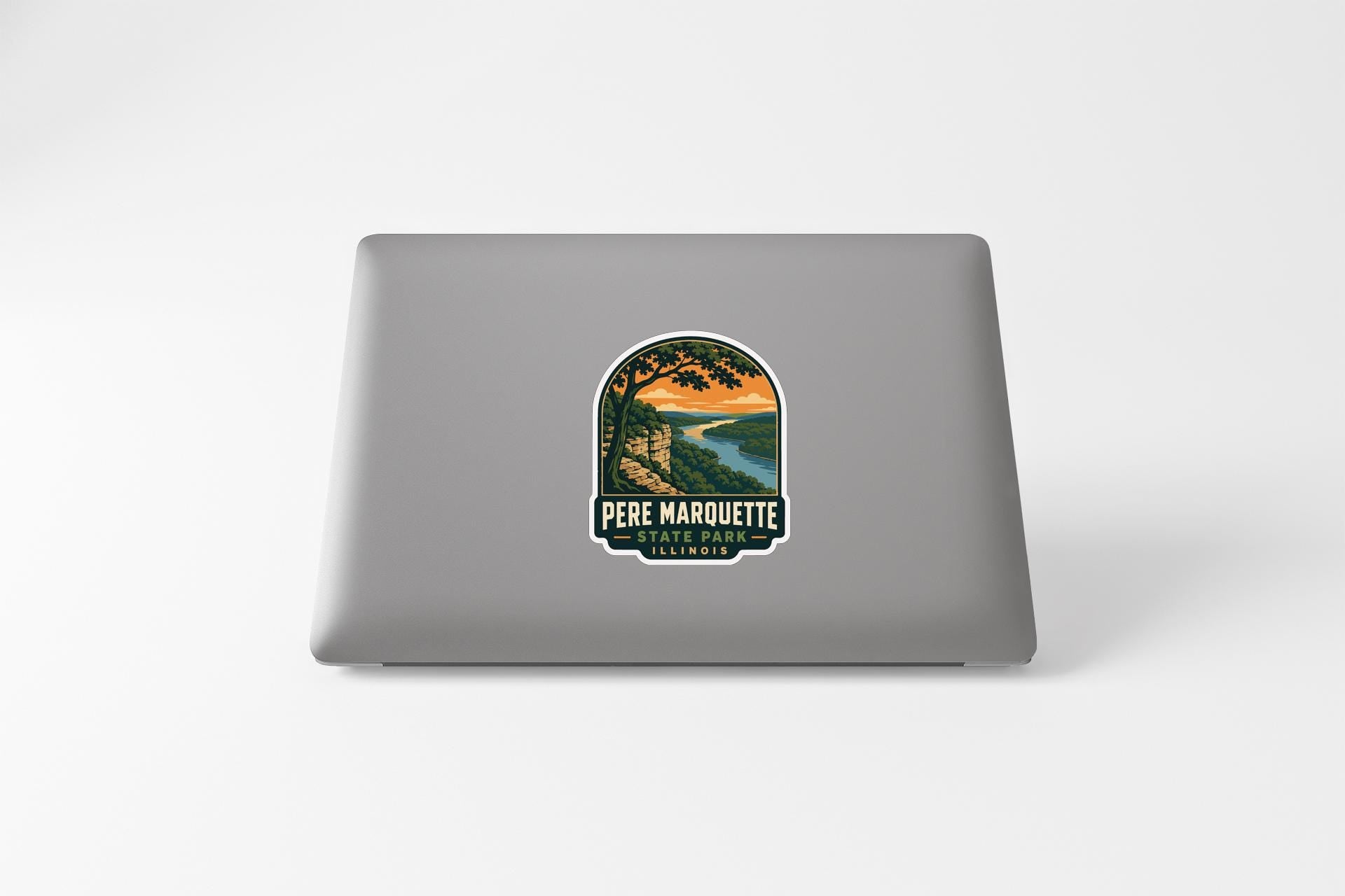 A sticker on the back of a laptop, depicting a scenic landscape with a river and mountains.